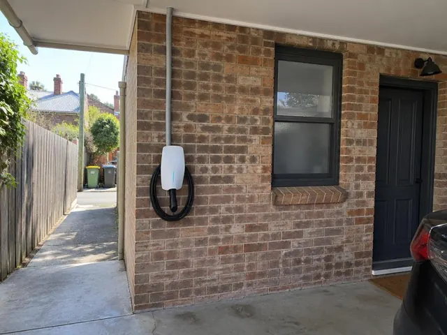 EV charger mounted on a brick house wall beside a window and door in Leichhardt
